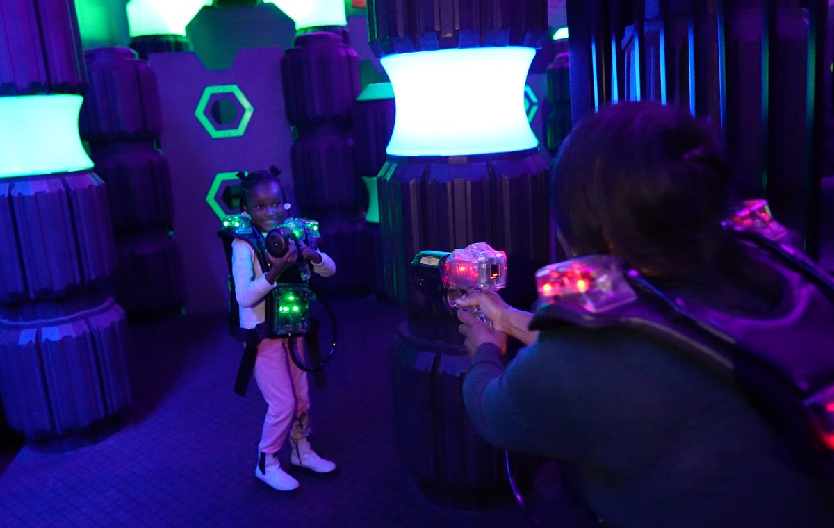 Guests playing Q-ZAR laser tag under neon arena lights